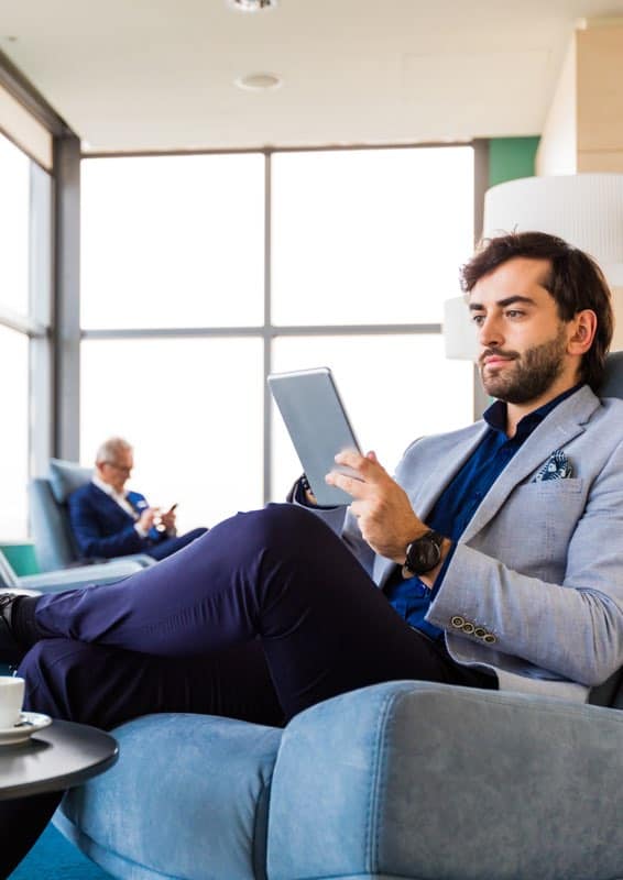 Moderner Geschäftsmann liest Tablet in Business-Lounge, beruflich, entspannt, Digital-Work, Business-Meeting, modernes Büro, Business-Workspace.