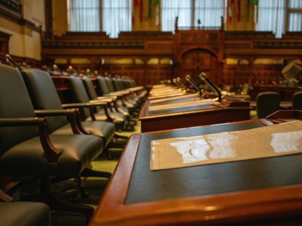 Leeres Sitzungslokal im Parlament, mit edlen Holz-Tischen und schwarzen Stühlen, ideal für politische Beratungen, Konferenzen oder Schulungen.