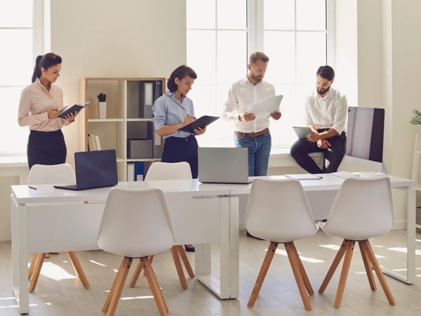 Moderner Konferenzraum mit vier Berufstätigen, die wichtige Dokumente besprechen, fördert produktive Meetings bei Slamanig Consulting & Training.