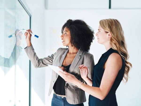 Modernes Business-Meeting, Frauen diskutieren an Whiteboard, Beratung, Strategie, erfolgreiche Zusammenarbeit, Team-Training, Präsentation, Innovation.