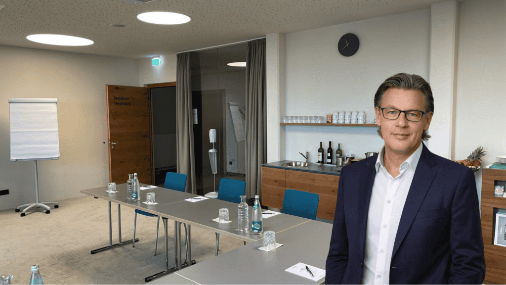 Heller, moderner Seminarraum mit Tisch, Stühlen, Whiteboard und Verpflegungsbereich, ideal für Workshops und Firmenveranstaltungen bei Slamanig Consulting & Training.